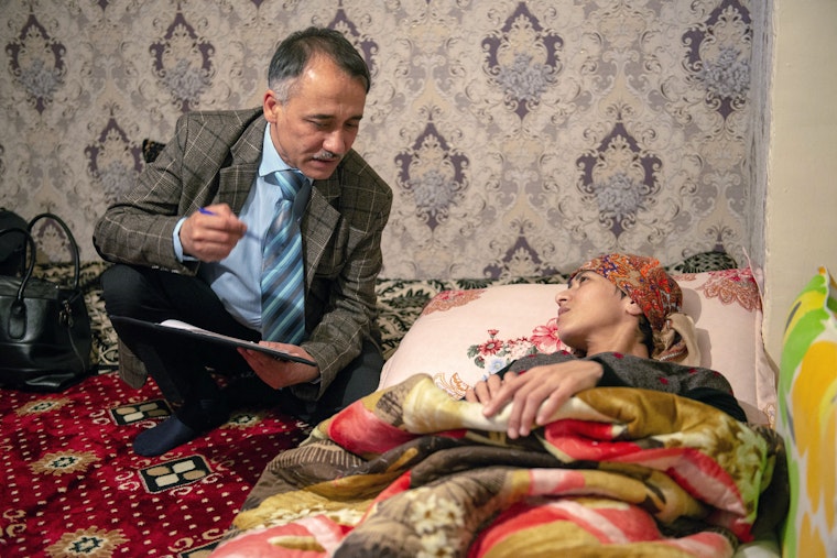 A physician with a mobile palliative care team visits a house-bound patient in Dushanbe, Tajikistan, on April 16, 2019. © Bakhriddin Isamutdinov for the Open Society Institute Assistance Foundation-Tajikistan A doctor speaks to a woman laying on a bed