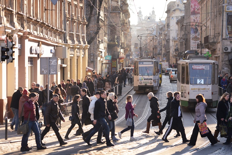 People walking across a street in front of trams