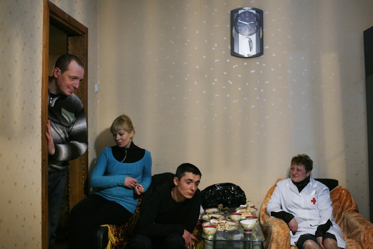 Several adults gather in a living room with a nurse