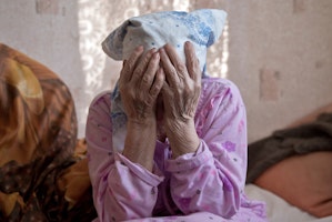 Elderly woman with her face in her hands