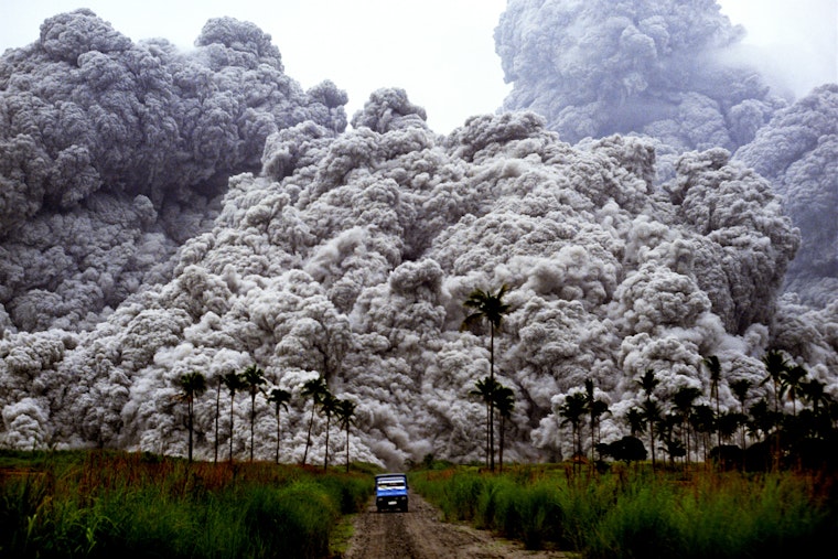 Photographers flee the intensifying eruption of Mount Pinatubo in Luzon, Philippines, on January 1, 1992. © Alberto Garcia/Saba Press Photos A car drives away from large plumes of smoke