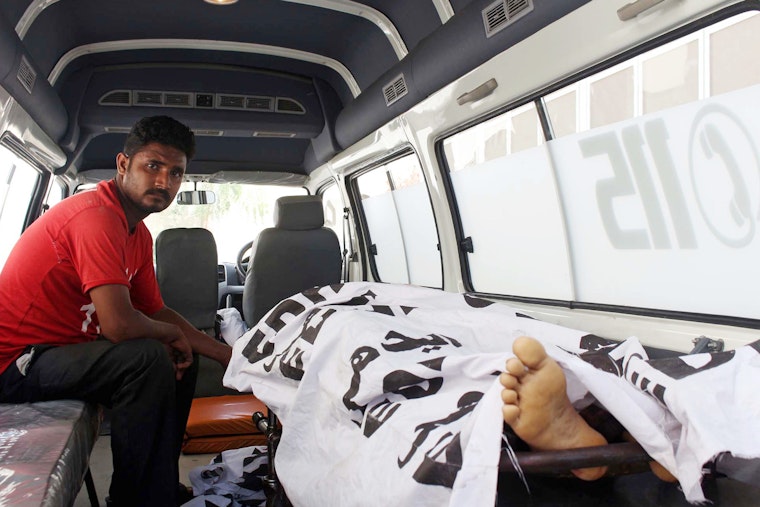 A man next to a covered body in an ambulance