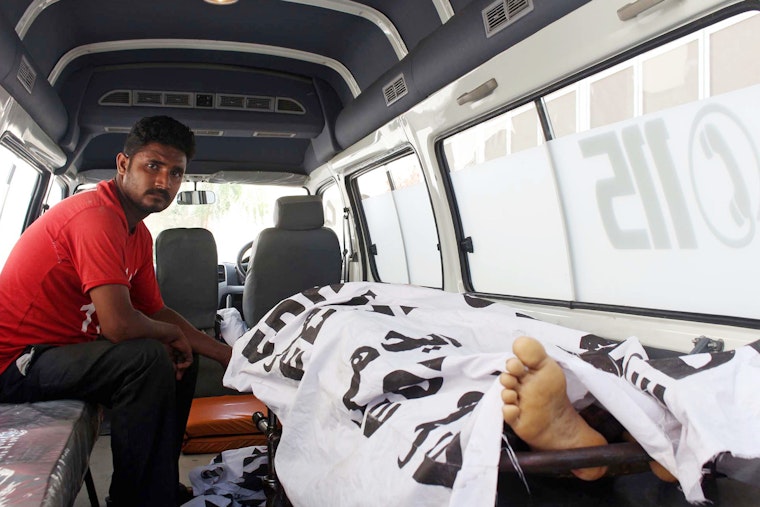 Rescue workers transport the body of a slain journalist to a hospital in Karachi on September 9, 2015. Photo credit: © Asianet Pakistan/Getty A man next to a covered body in an ambulance