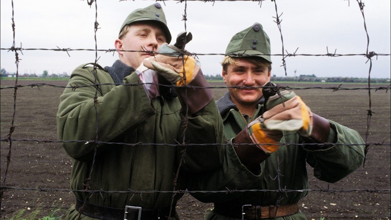 Two men using wire cutters to dismantle the fence at the Hungarian border on May 1, 1989. Photo credit: © Eric Bouvet/Gamma-Rapho/Getty Two men using wire cutters to cut a razor wire fence.
