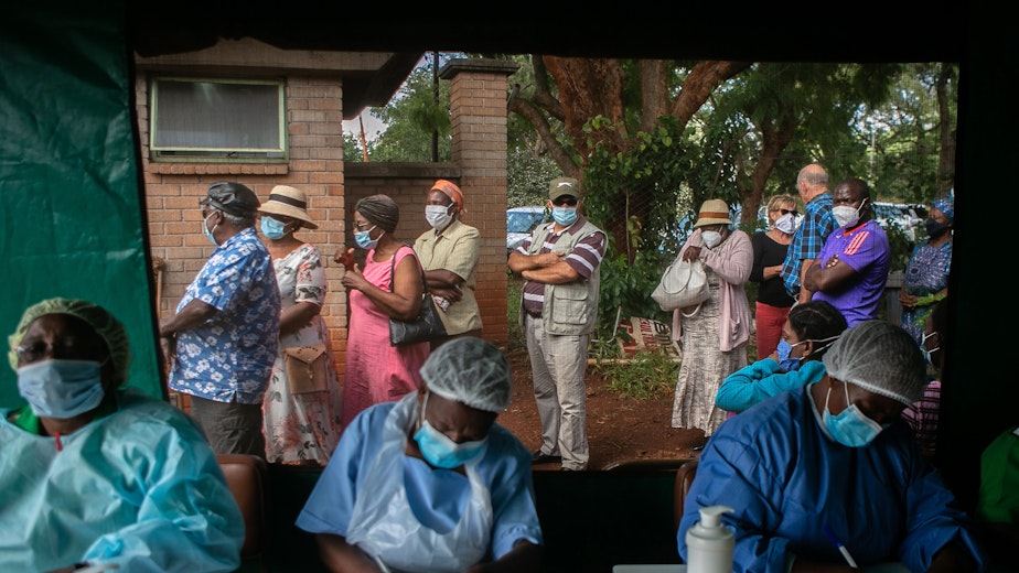 People wait outside a medical tent to receive a COVID-19 vaccine at a hospital in Harare, Zimbabwe, on March 29, 2021.