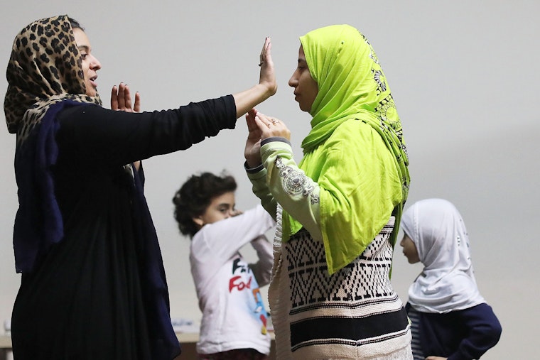 Women facing each other with arms raised