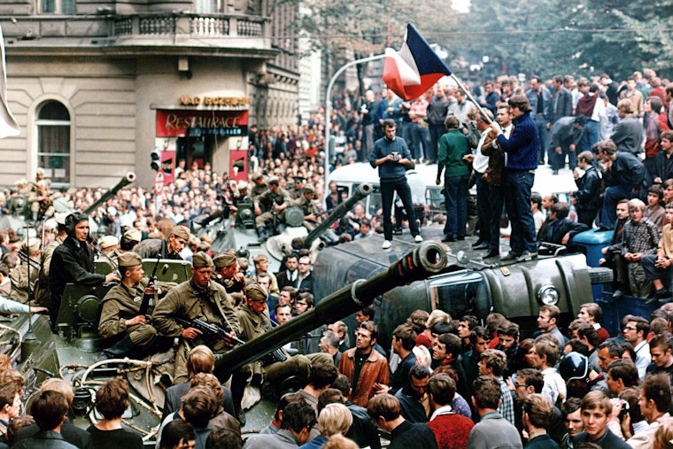 Czech youngsters holding a Czechoslovak flag stand atop an overturned truck as other residents surround Soviet tanks in Prague on August 21, 1968. Photo credit: © Libor Hajsky/Getty A crowd surrounds tanks