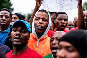 Employees and contractors demonstrate in front of the gates of a coal mine in Hendrina, South Africa, on February 22, 2018. Photo credit: © Marco Longari/AFP/Getty a group of men protesting