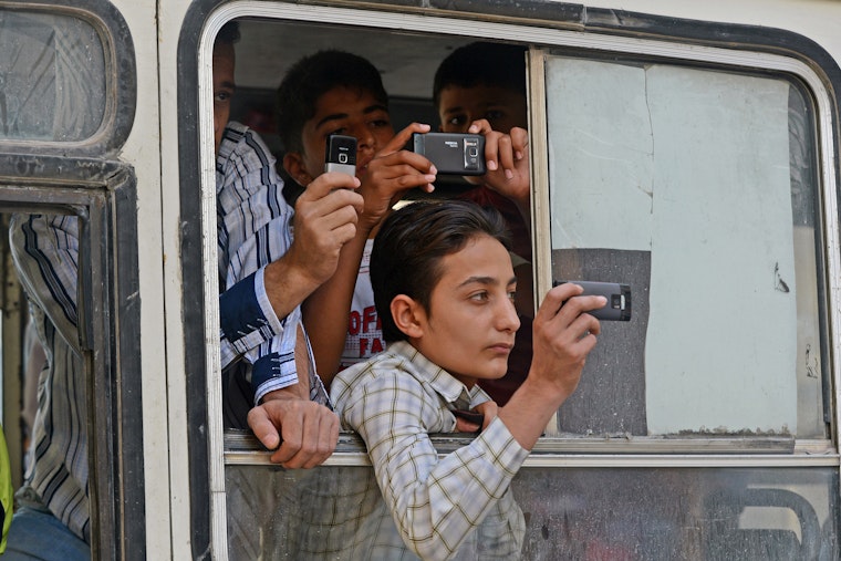 Young people film out of a bus window