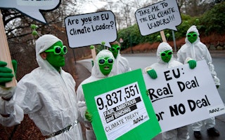 People wearing green face paint and costume antennae holding signs