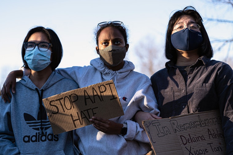 Three people attending a rally while wearing protective face masks
