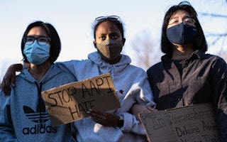 Three people attending a rally while wearing protective face masks