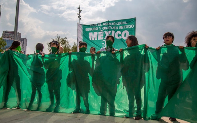 People stand behind a green banner in support of abortion legalization in Mexico City.