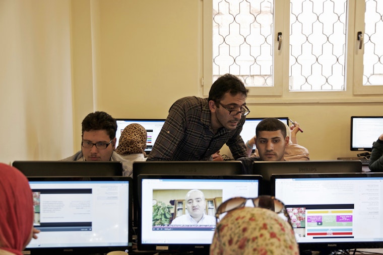 A teacher with students at computer stations