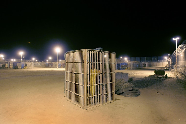 A juvenile detainee stands in a solitary confinement cage in Abu Ghraib on October 27, 2005. Photo credit: © John Moore/Getty A prison yard at night
