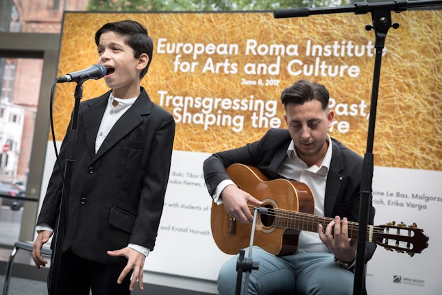 A boy singing next to a man playing guitar