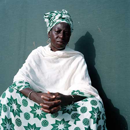 Woman in green dress sits with hands folded