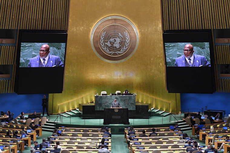 UN General Assembly, President Dennis Francis, speaking at the UN headquarters with his face appearing on two large screens behind him.