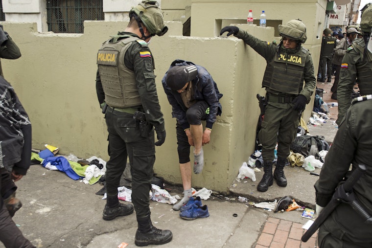 A man putting on a sock and surrounded by police officers