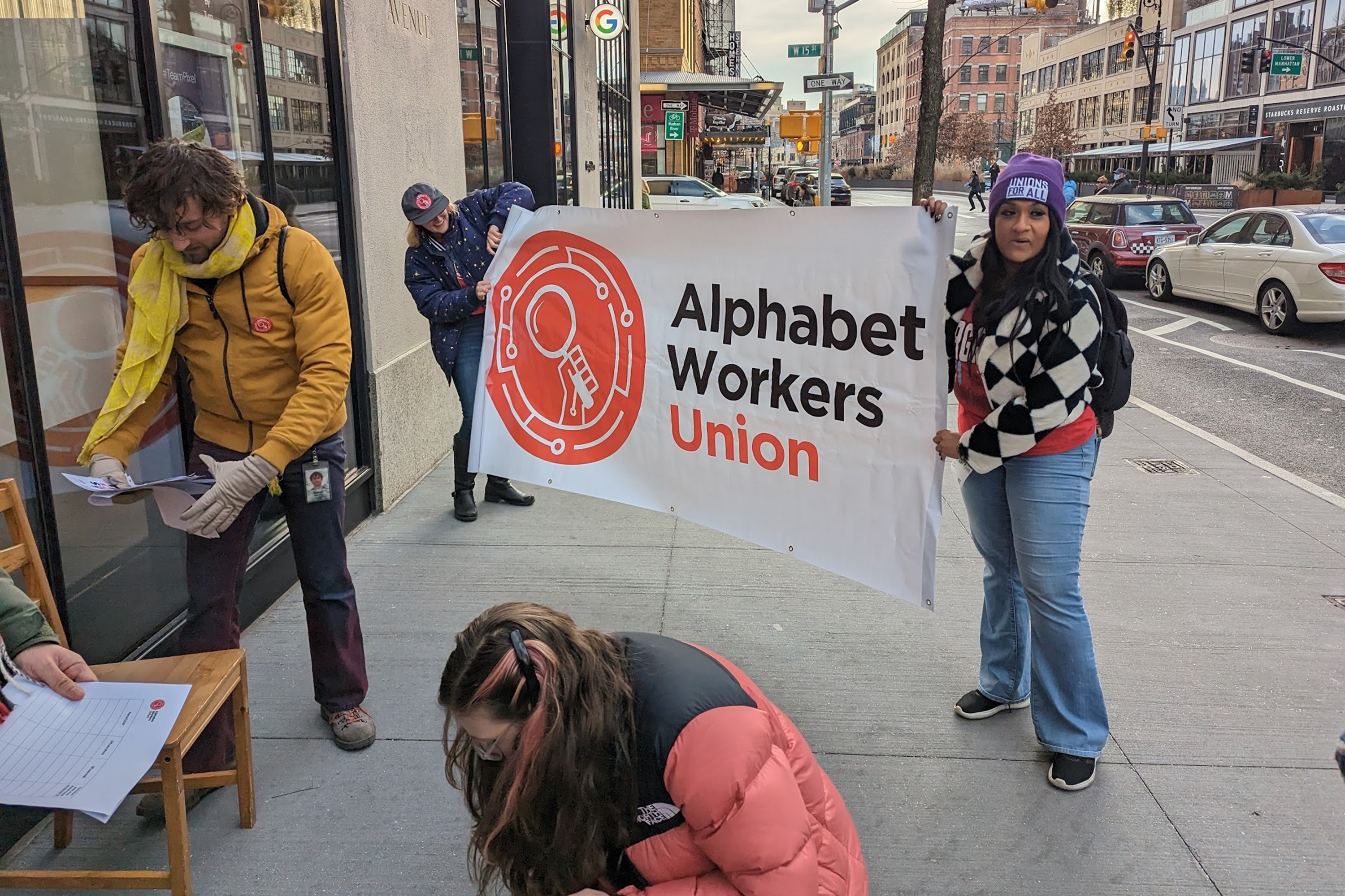 Individuals hold a sign outside a building that says "Alphabet Workers Union"