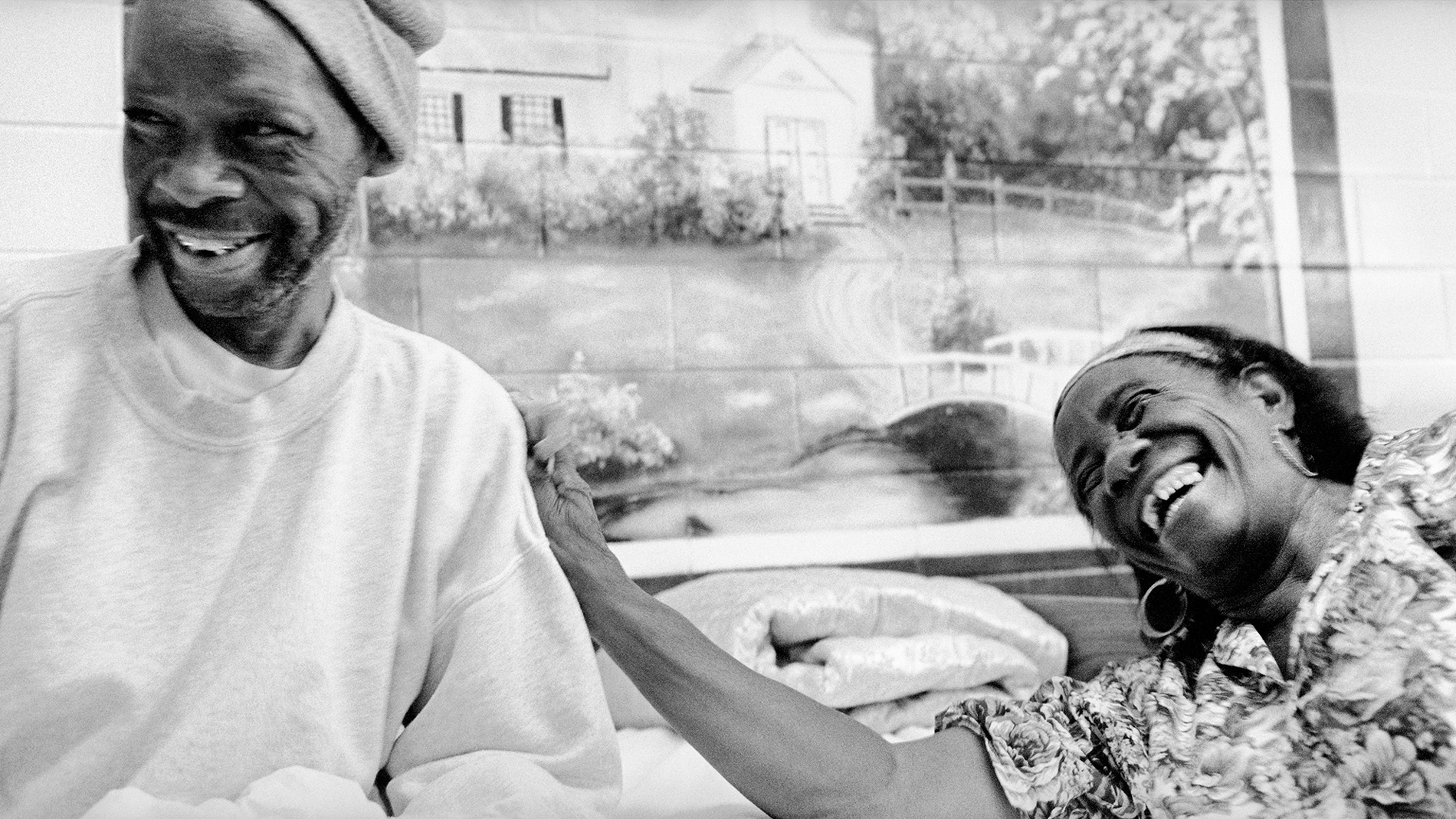 A woman holding the shoulder of a man as they both laugh