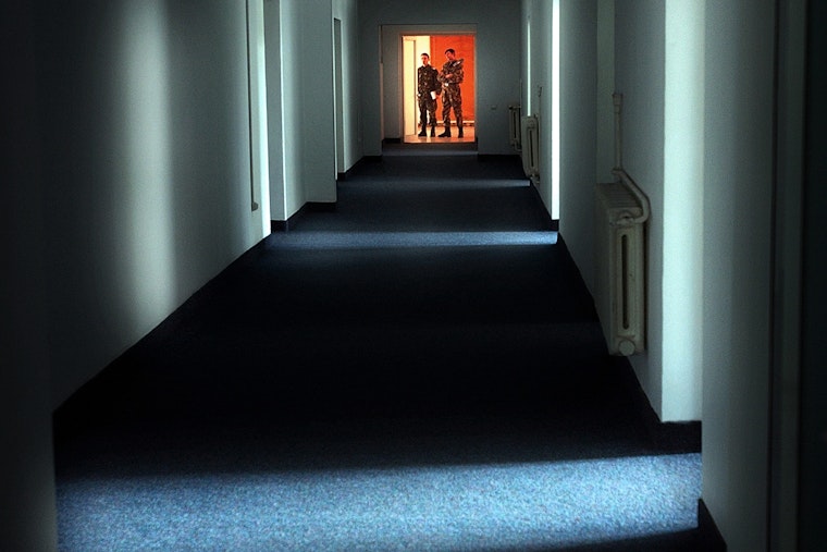 Military staff at an airbase near the Black Sea port of Constanta, Romania, on November 9, 2005. Photo credit: © Vadim Ghirda/AP/Shutterstock Two men in military garb stand at the end of a long, dark hallway.