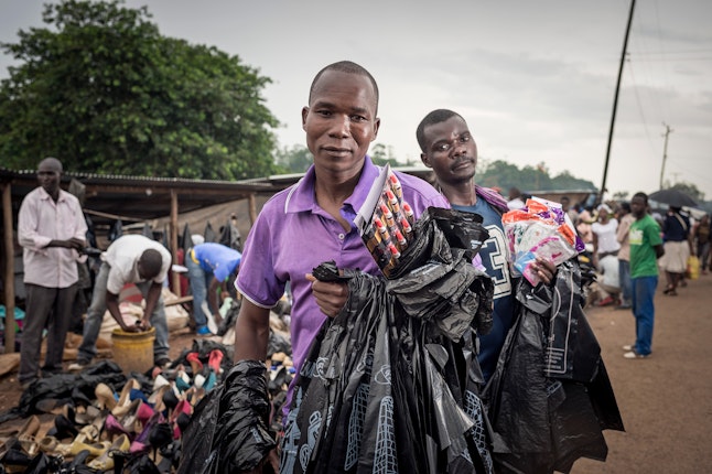 Men in a market holding plastic bags