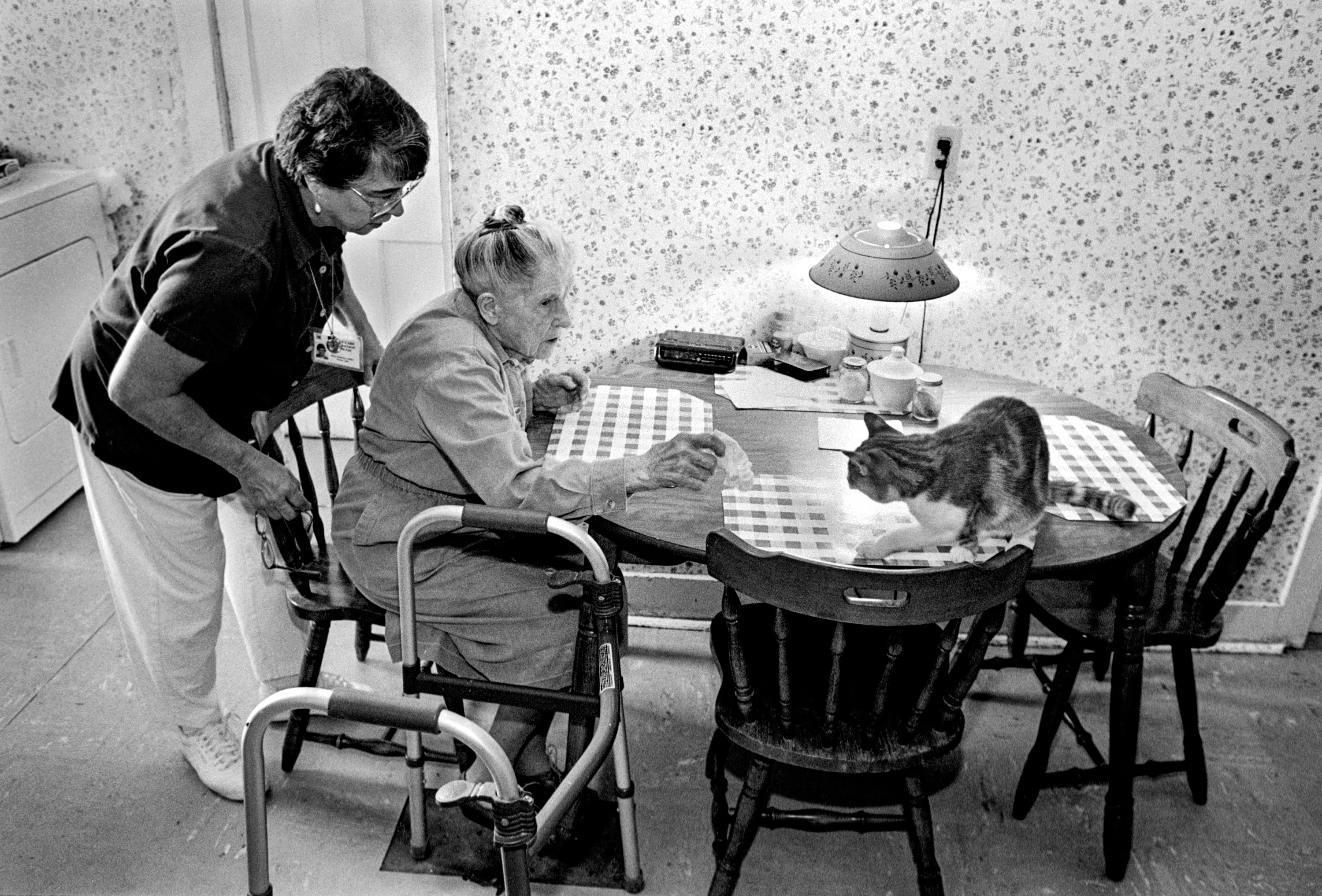A mother and daughter sit at the side of a sick man in the hospital