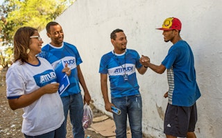 People wearing ATITUDE T-shirts smiling with a man