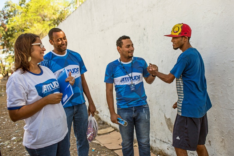 People wearing ATITUDE T-shirts smiling with a man