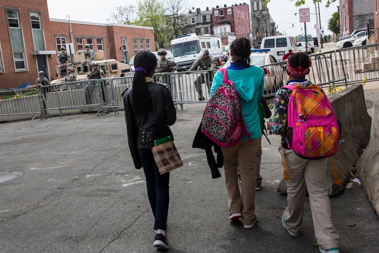 Children walk past National Guardsmen in Baltimore