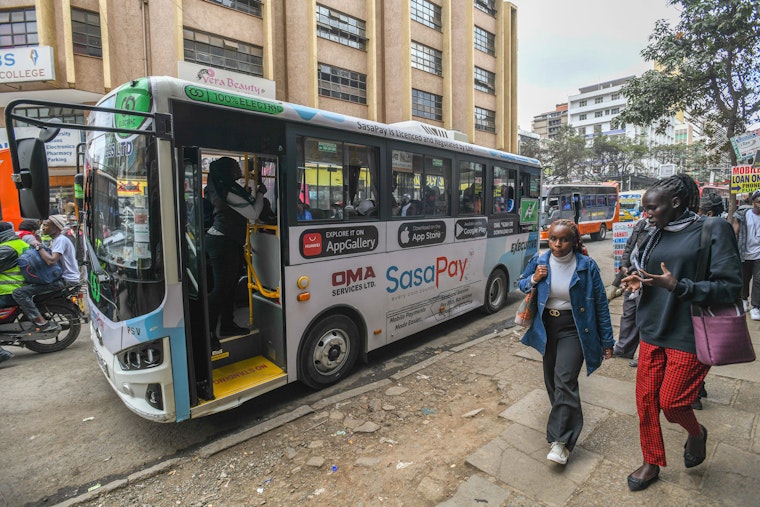 An electric bus picks up passengers.