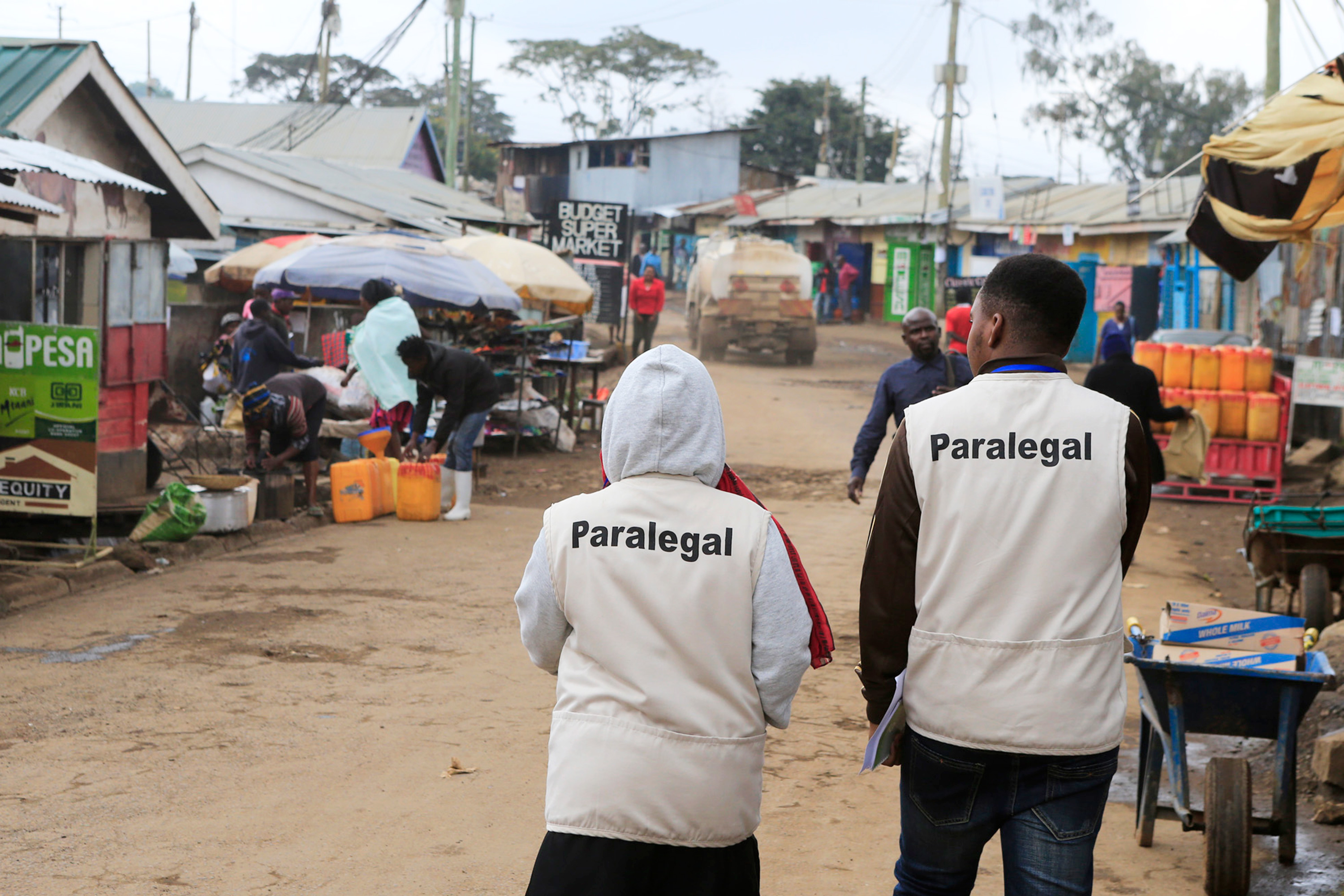 A man and a woman wearing vests that say “paralegal” walking down a road.