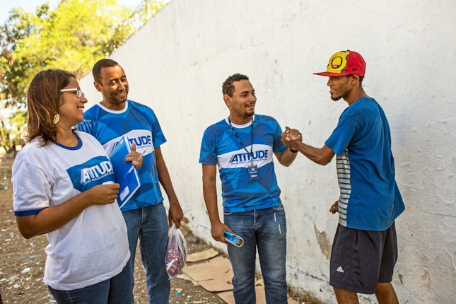 Three men and a woman engage in conversation while outdoors. All four are members of an Open Society grantee which focuses on providing care and support for drug users and their families.