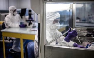 Two people in full-body protective gear in a laboratory
