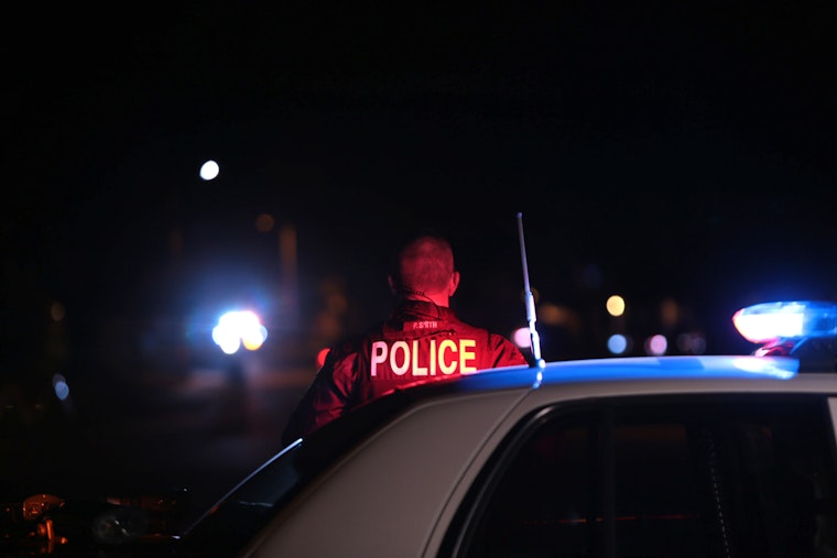 A police officer next to a police car at night