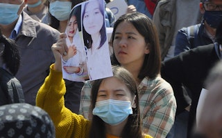 A woman holding up a picture among a crowd