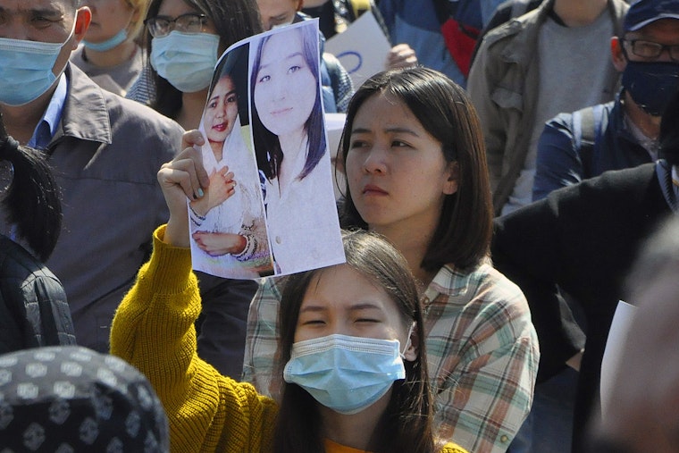 A woman holding up a picture among a crowd