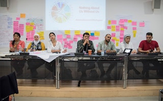The Global Refugee Network steering committee at the Global Summit of Refugees on June 26, 2018. Photo credit: © Global Refugee Network/Riccardo Pareggiani A group sits behind a table in front of a presentation.