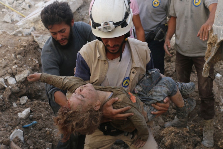 A man in a white helmet carrying a child