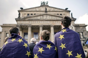 Three people wrapped in EU flags.