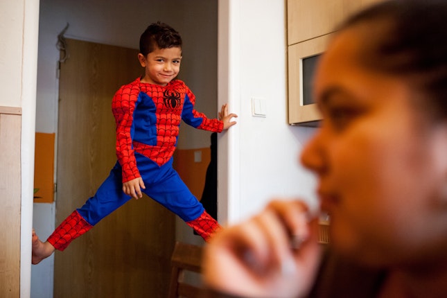 A boy in a costume climbs a door jamb