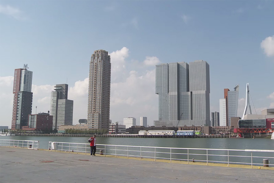 A man walking in foreground of a Dutch cityscape