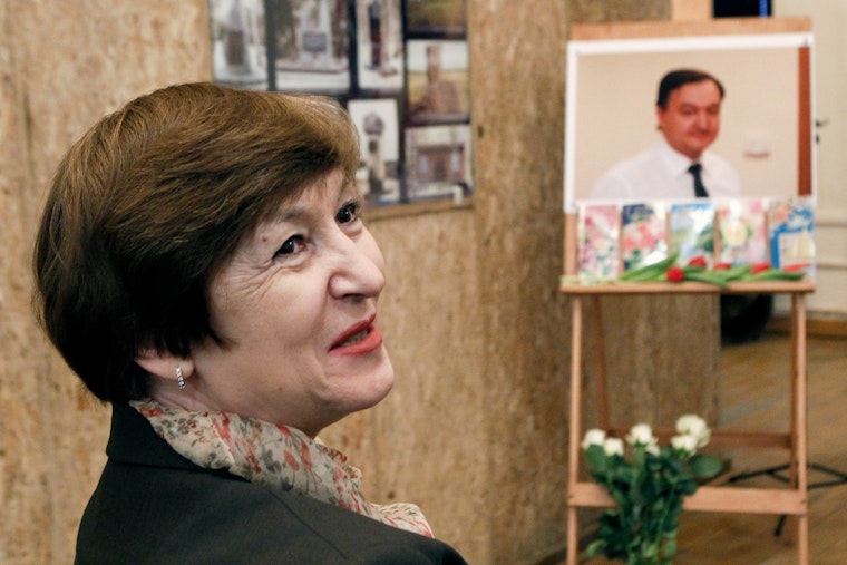 A mother in front of a photo of her deceased son.