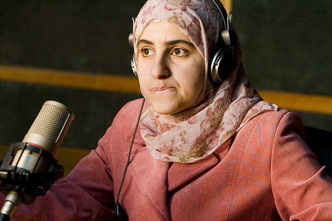 Women wearing headphones and sitting at microphone