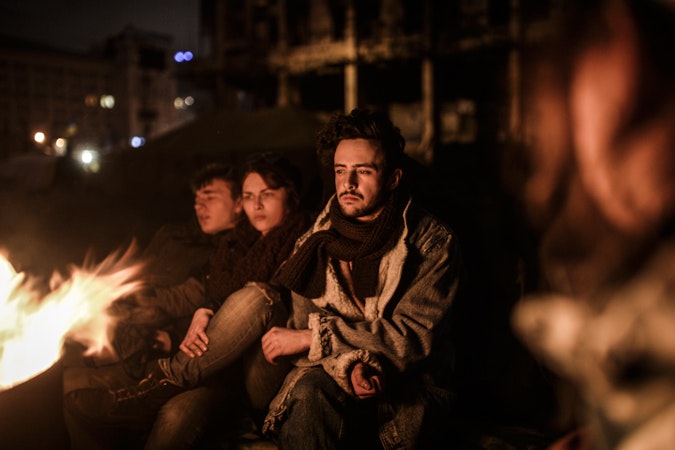 Ukrainian youths sit near a fire late into the night in Kyiv’s Maidan on February 25, 2014. The day before Ukraine had issued an arrest warrant to oust President Viktor Yanukovych over the “mass murder” of protesters, and also appealed for $35 billion in Western aid to pull the crisis-hit country from the brink of economic collapse. The dramatic announcements by the ex-Soviet nation’s new Western-leaning team, approved by parliament—saw the pro-Russian leader, President Viktor Yanukovych, go into hiding—as a top EU envoy arrived in Kyiv. Photo credit © Bulent Kilic/AFP/Getty Images Ukraine youths by fire