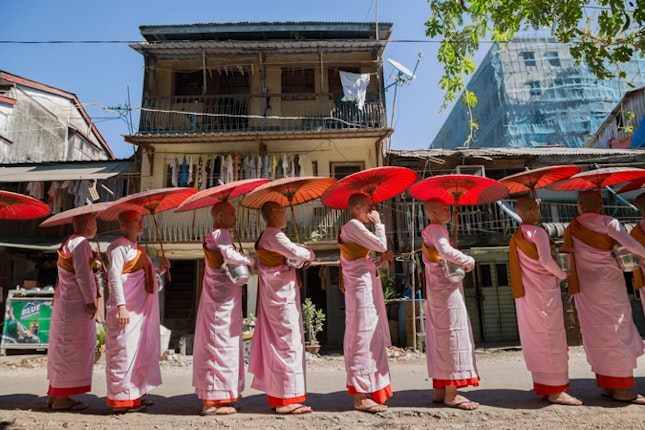 Buddhist nuns chant as they seek rice and alms in Yangon, Burma on December 20, 2012. Most Burmese are devout Buddhists, and nuns and monks are the spiritual backbone of Burmese society. In 2007, they were on the front lines of the Saffron Revolution against the military regime. Photo credit: © Ed Kashi/VII for the Open Society Foundations Buddhist nuns lined up