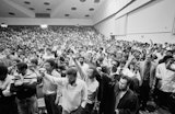 A hall full of students with their fists in the air