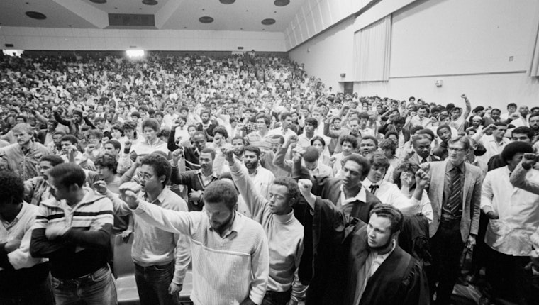 A hall full of students with their fists in the air