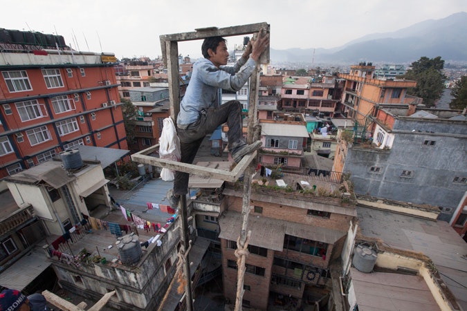 Om Kumar Chaudhary, age 23, fixes a goods lift on a construction site in Kathmandu, Nepal, on December 16, 2013. He moved to Kathmandu to learn construction work in preparation for a job in Qatar. He currently earns $180 a month but expects to earn more than double that amount in Qatar. Photo caption: © Narendra Shrestha/EPA A man on a scaffolding